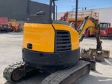 a yellow and black excavator sitting on top of a dirt field