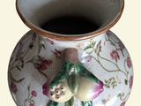 a small vase with a bird on it sitting on a table