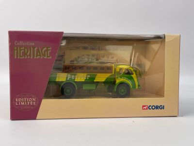 un petit camion-jouet dans une boîte, posé sur une surface blanche, avec une boîte rose à côté