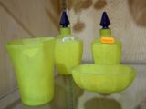 trois vases jaunes et un bol posés sur une étagère en verre