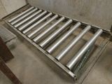 une photo d'un tapis roulant en acier inoxydable dans un entrepôt