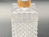 a clear glass bottle with a gold lid on a table