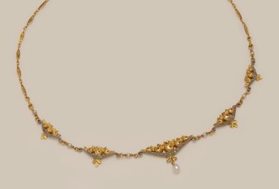 a close up of a gold necklace with pearls on it