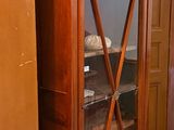 a wooden cabinet with a glass door in the corner of the room
