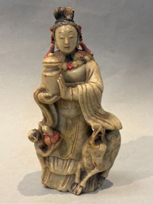 statue d'une femme assise sur un rocher, avec un oiseau sur l'épaule