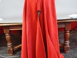 a red cloak on a mannequin in front of a pool table