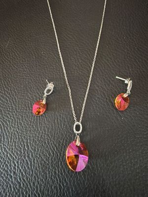 un ensemble composé d'un collier et de boucles d'oreilles ornés de cristaux roses sur un fond en cuir noir