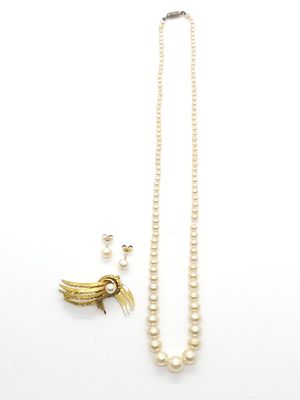 un collier de perles blanches orné d'un pendentif en forme d'oiseau en or et une paire de boucles d'oreilles
