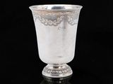 une coupe ancienne en argent posée sur une surface noire, avec un fond noir