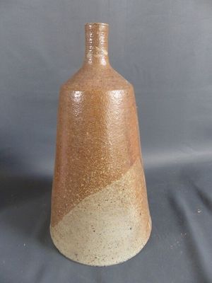 un vase brun posé sur une table à fond gris