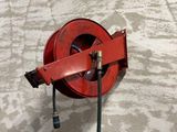 une lance à incendie rouge fixée au mur à côté d'une horloge