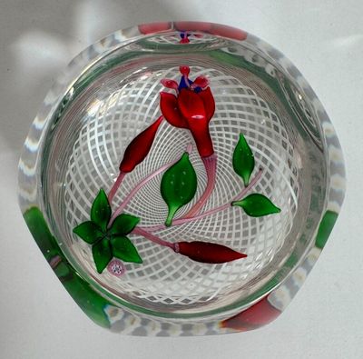 a glass bowl with a red flower and green leaves on it