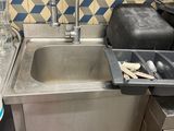 a sink in a kitchen with a trash can and a trash can
