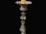 an old fashioned candle holder with a candle on top of it