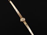 a gold watch on a black surface with a black background
