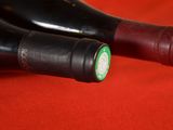 two bottles of wine that are sitting on a red cloth