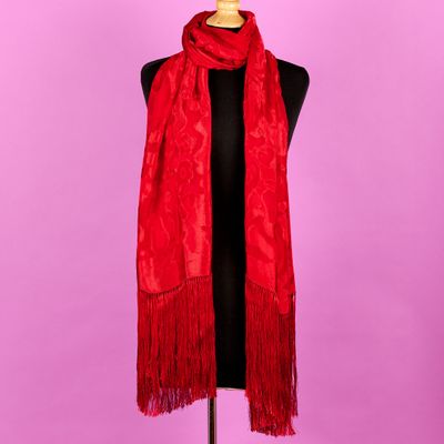 une écharpe rouge posée sur un mannequin, devant un fond violet