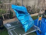 a cart that has a blue bag on it in the yard