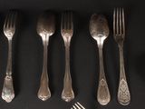many forks and spoons laid out on a table