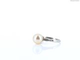 a ring with a pearl on it sitting on a white surface