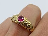 a close up of a person ' s hand holding a gold ring with a ruby stone