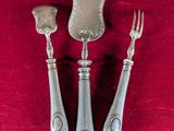 three pieces of silverware on a red cloth with a spoon, fork and knife