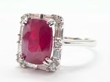 a close up of a ring with a red stone surrounded by white diamonds