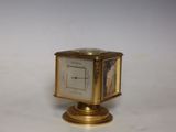 a small clock sitting on top of a gold stand