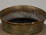 a bronze vase with writing on it sitting on a table