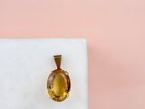 an oval citrine stone pendant on a white marble block