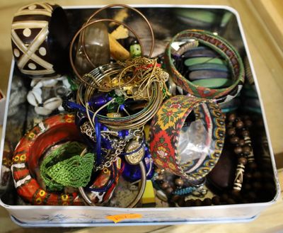 a metal container filled with assorted jewelry on a table