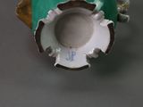 a green and white vase that has a hole in it