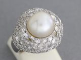 a close up of a pearl and diamond ring on a white surface