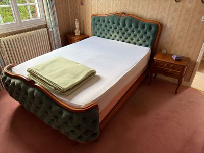 a bed with a green headboard and a green blanket on top of it