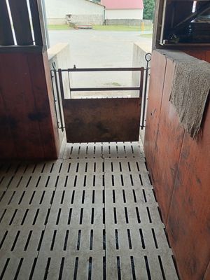 un box à chevaux dont la porte est ouverte et sur laquelle est accrochée une serviette