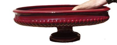 a hand that is holding a red bowl with a spoon in it