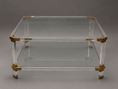 une table basse en verre transparent et en laiton, dotée de deux étagères
