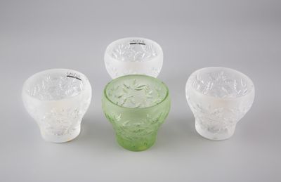 trois vases en verre vert posés les uns à côté des autres sur une surface blanche