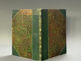 un vieux livre à la couverture verte posé sur une table blanche