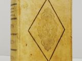 an old book with a gold cover on a white surface
