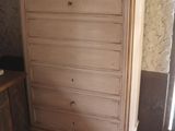 a dresser in the corner of a room with a vase on top of it