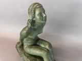 statue of a woman sitting on a rock on a white background