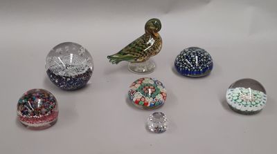 un petit oiseau perché sur une table, à côté de nombreuses boules de verre