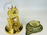two clocks sitting under a glass dome on a table