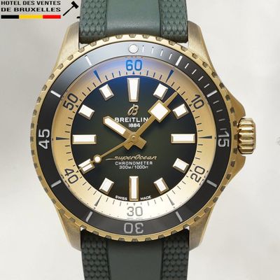 une montre dorée et noire avec un bracelet vert