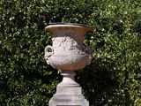 a stone urn sitting in the middle of a garden