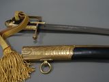 an old sword with a gold handle and tassel on a table