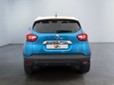 the rear end of a blue and white car in a white room