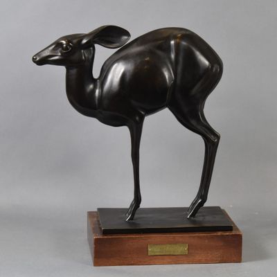 bronze statue of a deer on a wooden base on a gray background