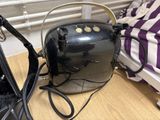 a black toaster sitting on a wooden table next to a window